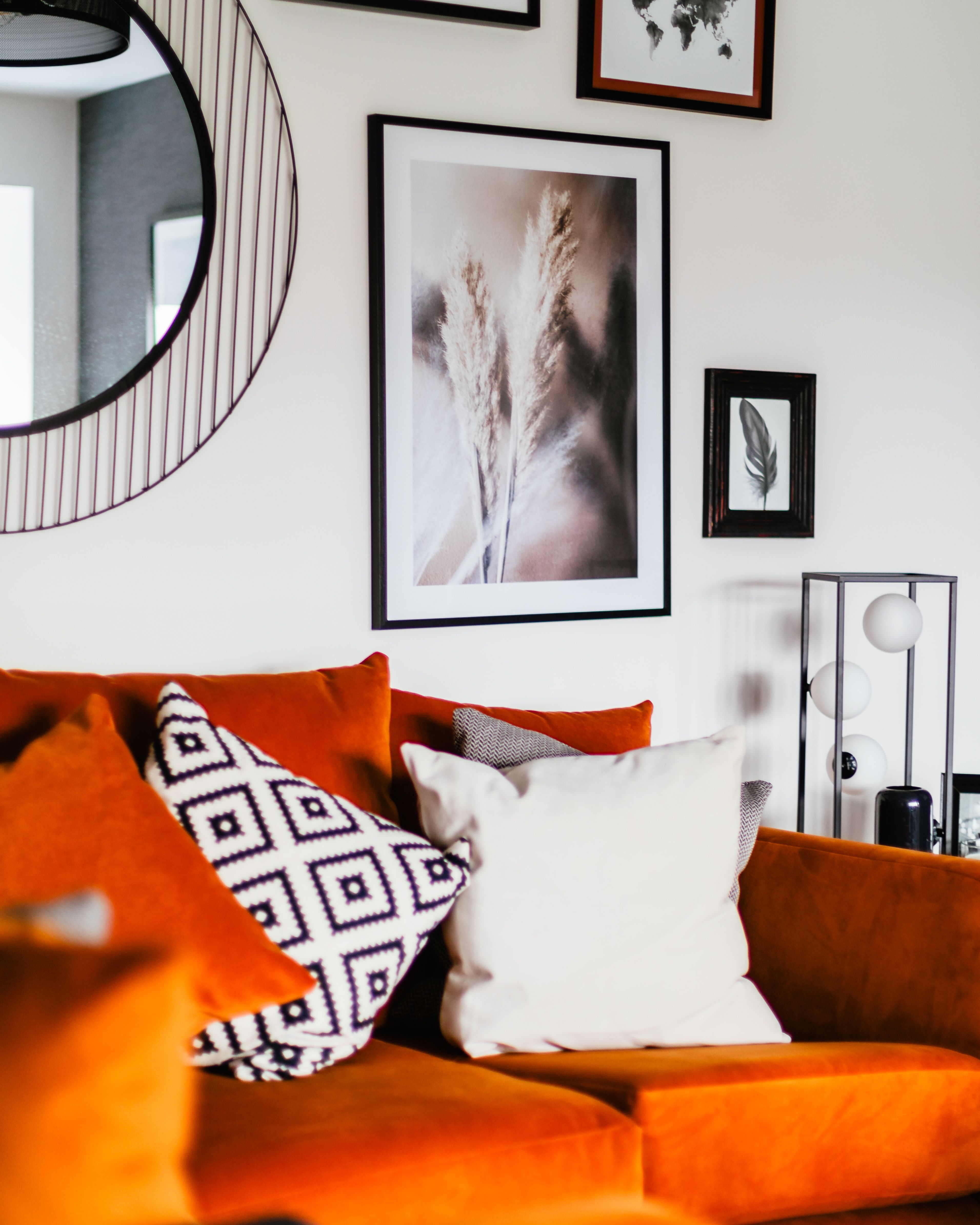 Orange couch in neutral living room against wall with pictures